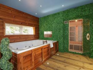 a bathroom with a bath tub and green walls at 9 Meadow Retreat in Liskeard
