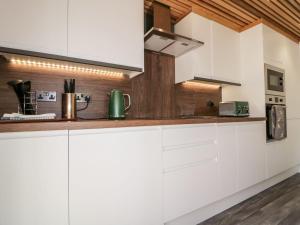 24 Meadow Retreat في ليسكيرد: مطبخ بدولاب بيضاء وسقف خشبي