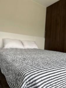 a bed with white sheets and pillows in a room at Apartamento Nuevo con Hermosa Vista, Ubicación Perfecta in La Paz
