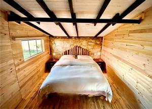 1 dormitorio con 1 cama en una habitación de madera en Sidarta, Casa Grande - Bella Casita, Casa Pequeña, en Chocontá