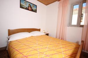 a bedroom with a bed with a yellow comforter and a window at Holiday house with WiFi Ustrine, Cres - 8037 in Ustrine