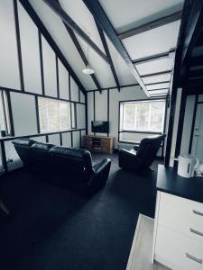 a living room with black leather furniture and windows at Chatsworth Cottage in Upper Hutt