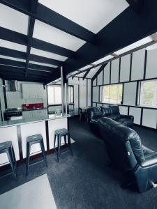 a living room with black leather furniture and a kitchen at Chatsworth Cottage in Upper Hutt