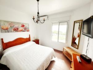 ein weißes Schlafzimmer mit einem Bett und einem TV in der Unterkunft Apartamento Playas del Sur in El Portil