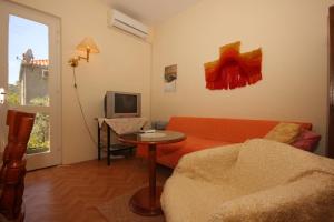 a living room with a orange couch and a tv at Apartments and rooms with parking space Srebreno, Dubrovnik - 8959 in Mlini