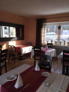 uma sala de jantar com mesas e cadeiras e uma janela em Hotel Achilles em Kirkel