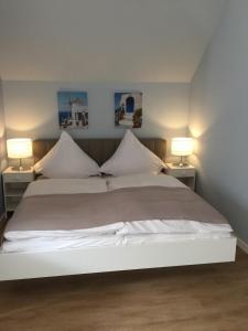 a bedroom with a white bed with two lamps at Hotel Achilles in Kirkel