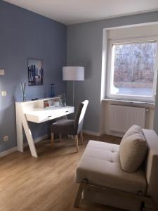 a living room with a desk and a chair and a couch at Hotel Achilles in Kirkel