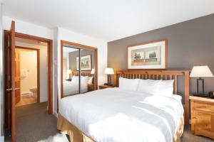 a bedroom with a large white bed and a bathroom at Northstar at Stoney Creek by Whiski Jack in Whistler