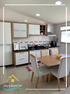 uma cozinha com uma mesa de madeira e armários brancos em Angra Hostel 147 em Angra dos Reis