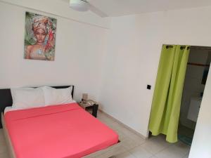 - une chambre avec un lit rouge et un rideau vert dans l'établissement Rayon de Soleil T2 Bas de villa, à Sainte-Anne
