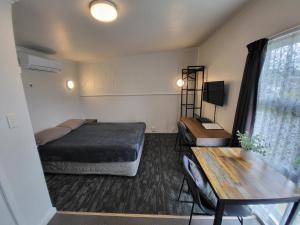 a bedroom with a bed and a desk and a table at Rockfield Motel in Auckland