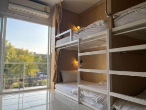 a room with bunk beds and a window with a balcony at Potae's House in Chiang Mai