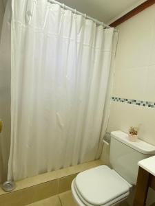 y baño con cortina de ducha blanca y aseo. en La Tante en San Carlos de Bariloche