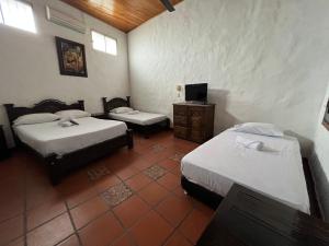 Zimmer mit 2 Betten und einem TV. in der Unterkunft Hotel Boutique Mirador Las Palmas in Honda