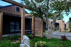 a log cabin with a picnic table and a tree at Cape Cod Veranda in South Yarmouth