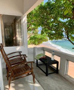 - une chaise et une table sur une terrasse couverte avec vue sur la plage dans l'établissement Sea view Villa, à Unawatuna