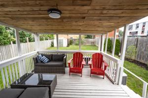 - une terrasse couverte avec 2 chaises rouges et un canapé dans l'établissement Cozy 4-Bdrm Pet-Friendly East Hamilton Escape, à Hamilton