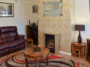 a living room with a fireplace and a leather couch at Tabusintac in Heacham