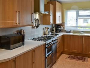 a kitchen with wooden cabinets and a stove top oven at Tabusintac in Heacham