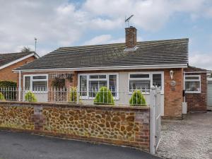 a brick house with a white fence in front of it at Tabusintac in Heacham