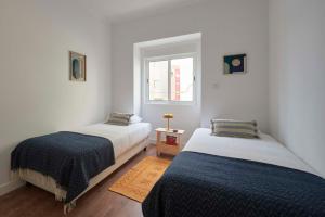 2 camas en una habitación con paredes blancas y ventana en Spacious & Light-Filled 4BR Apartment By TimeColer, en Amadora