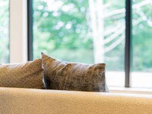 a pillow sitting on a couch in front of a window at Rakuten STAY VILLA Aso Kurokawa -102 1LDK Capacity of 6 persons in Minamioguni