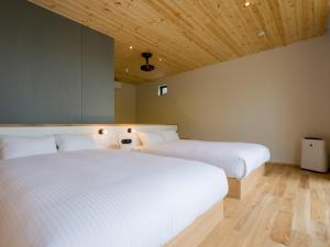 2 łóżka w pokoju z drewnianym sufitem w obiekcie Rakuten STAY VILLA Aso Kurokawa -104 1LDK pet allowed Capacity of 6 persons w mieście Minamioguni
