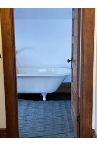 a white bath tub sitting in a bathroom through a door at Grand Old White Artist's Loft in Charleston