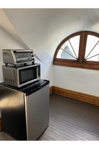 a room with a microwave on top of a refrigerator at Grand Old White Artist's Loft in Charleston