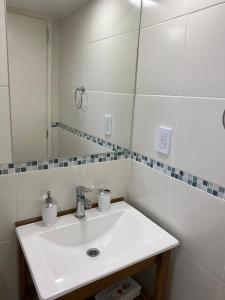 La salle de bains est pourvue d'un lavabo blanc et d'un miroir. dans l'établissement La Tante, à San Carlos de Bariloche