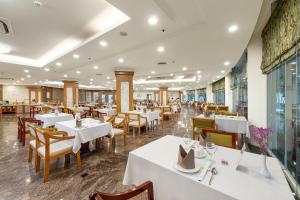 a restaurant with white tables and wooden chairs at Sunflower International Village in Hai Phong