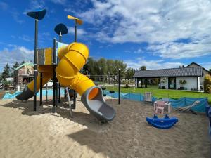 a playground with a yellow slide in the sand at Comfortable holiday houses with air conditioning close to the sea, Sianozety in Sianozety
