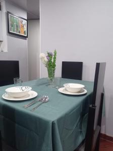 une table avec un tissu de table vert, des assiettes et de l'argenterie dans l'établissement Apartamento Amoblado en Facatativá, à Facatativa