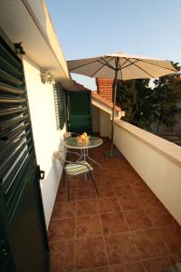 a table and chair on a balcony with an umbrella at Apartment and Room Lada in Sumartin