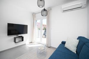 Una sala de estar con un sofá azul y un televisor en House Luxury Konforta, en Brodarica