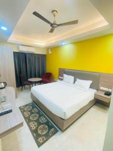 een slaapkamer met een wit bed en een gele muur bij Royal Beach International in Puri