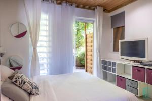 una camera con letto, TV e finestra di Magnifique et spacieux T2 proche de la plage - La Kiss House a Deshaies
