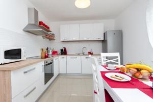 - une cuisine avec des placards blancs et une table avec une serviette rouge dans l'établissement Apartment Ivona, à Tribalj
