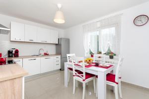 a white kitchen with a white table and chairs at Apartment Ivona in Tribalj