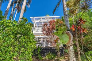 una casa blanca con palmeras delante en Lower Decks, en Byron Bay