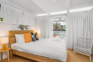1 dormitorio blanco con 1 cama y 1 silla en Lower Decks, en Byron Bay