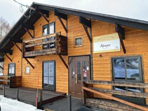 a log cabin in the snow with the front door open at Alpages madarao in Madarao Kogen