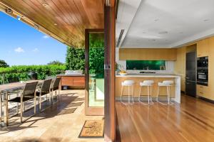 an open kitchen with a bar with stools and a balcony at Villa Gabrielle in Byron Bay