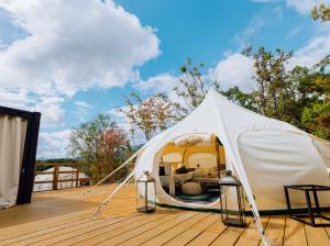 a white tent on top of a wooden deck at Yufuin Glamping COMOREBI in Yufu