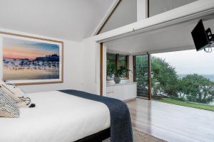 a bedroom with a bed and a large window at Belongil Beach House in Byron Bay