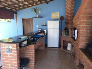 a kitchen with a white refrigerator and a brick wall at Casa Brasil pousada e lazer in Trindade