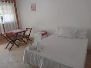 a bedroom with a bed and a table and chairs at Casa Brasil pousada e lazer in Trindade