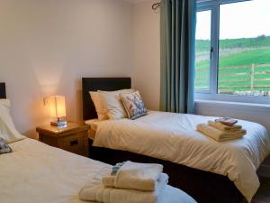two beds in a room with a window and towels at Inverallan in Amisfield Town