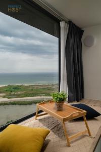 uma sala de estar com uma mesa e uma grande janela em Imperio Residence Seafront by Perfect Host em Malaca